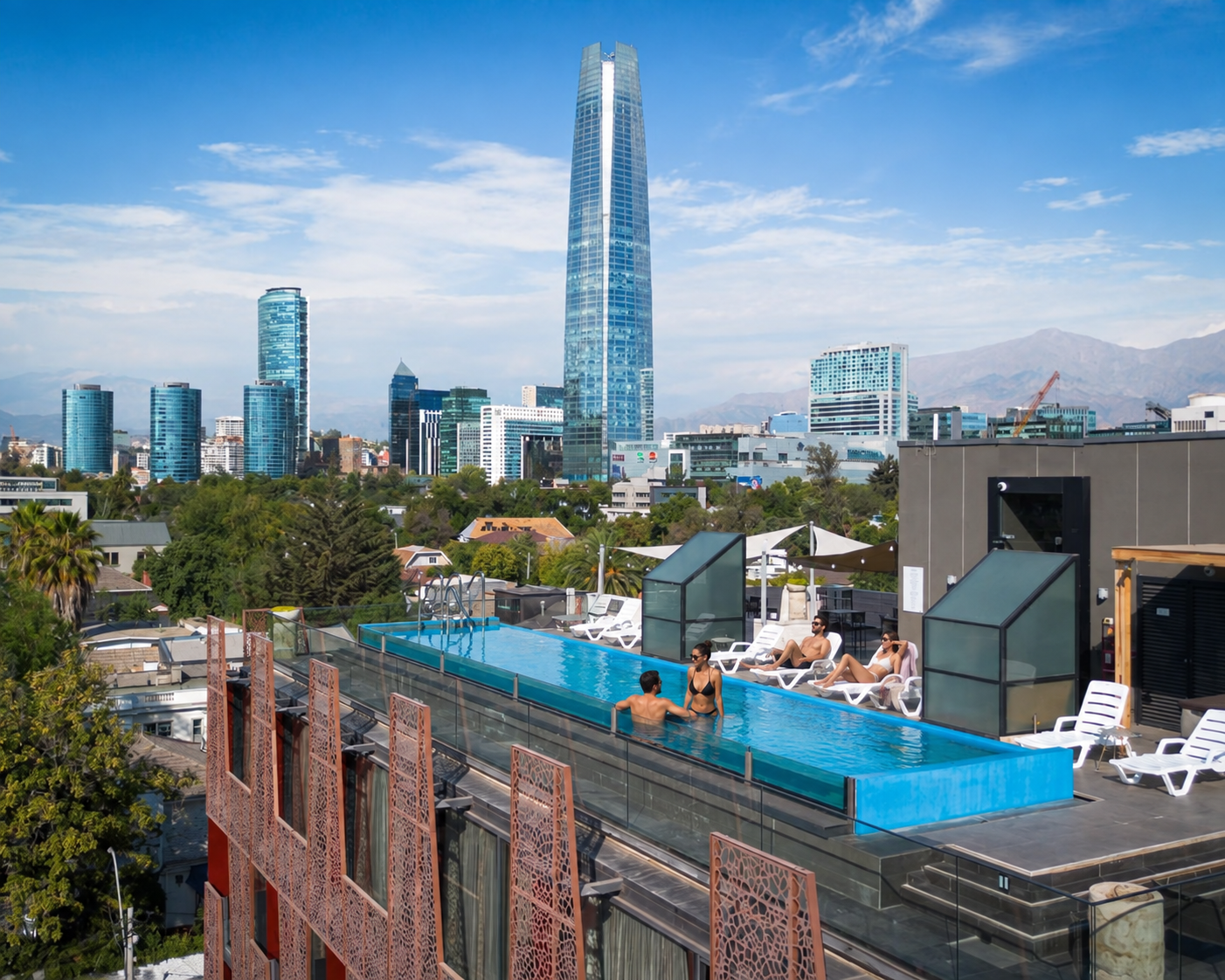 Huéspedes disfrutando de la piscina en la terraza de Hotel Ladera, con vista a Santiago